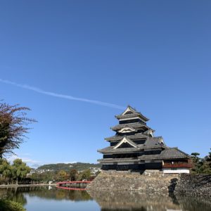わずかに見える北アルプスをバックにした松本城天守